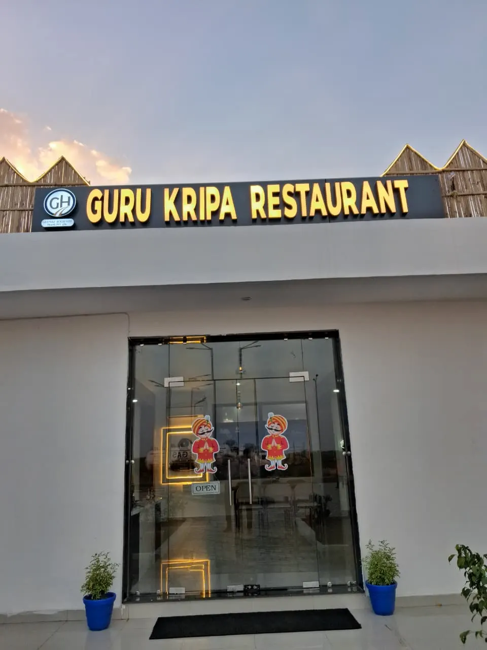Glass entrance of Guru Kripa Restaurant under its lit signboard